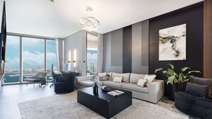 A spacious living room with a large window offering a city view, a modern black coffee table, and a grey sofa set.