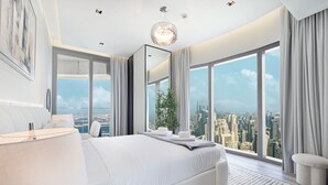 A modern bedroom with a large bed, a city view, and a chandelier.