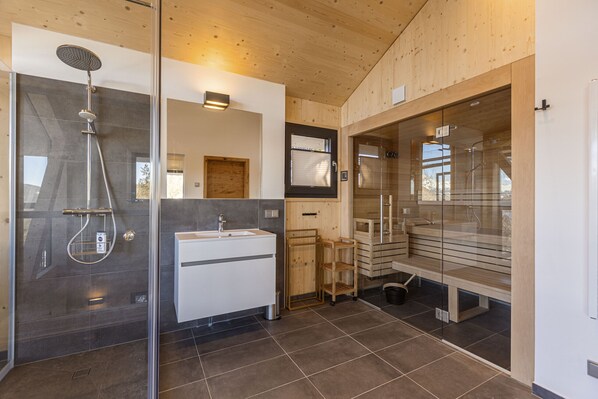 Une salle de bain moderne avec une douche à parois de verre, un lavabo blanc et un meuble-lavabo en bois.