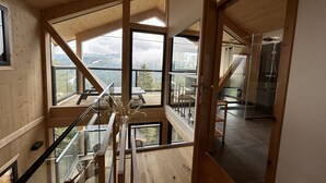 A modern interior with wooden beams, large windows, and a glass railing. - Superior Chalet III with Sauna & Hot Tub (Turrach)