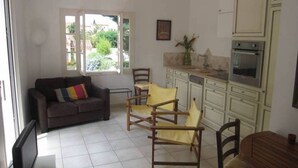 A living room with a sofa, chairs, a dining table, and a kitchen with cabinets and appliances. - 60 m2 apartment 250 m from the beach (Argelès-sur-Mer)