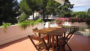 A wooden table and chairs on a terrace with a white wall and greenery. - 60 m2 apartment 250 m from the beach (Argelès-sur-Mer)