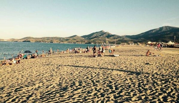 A beach with people, tents, and mountains in the background.