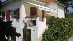 A two-story house with a white exterior, red-tiled roof, and a balcony with potted plants. - 60 m2 apartment 250 m from the beach (Argelès-sur-Mer)
