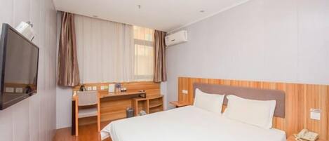 Une chambre d’hôtel avec un lit, un bureau, une télévision et une fenêtre avec des rideaux.