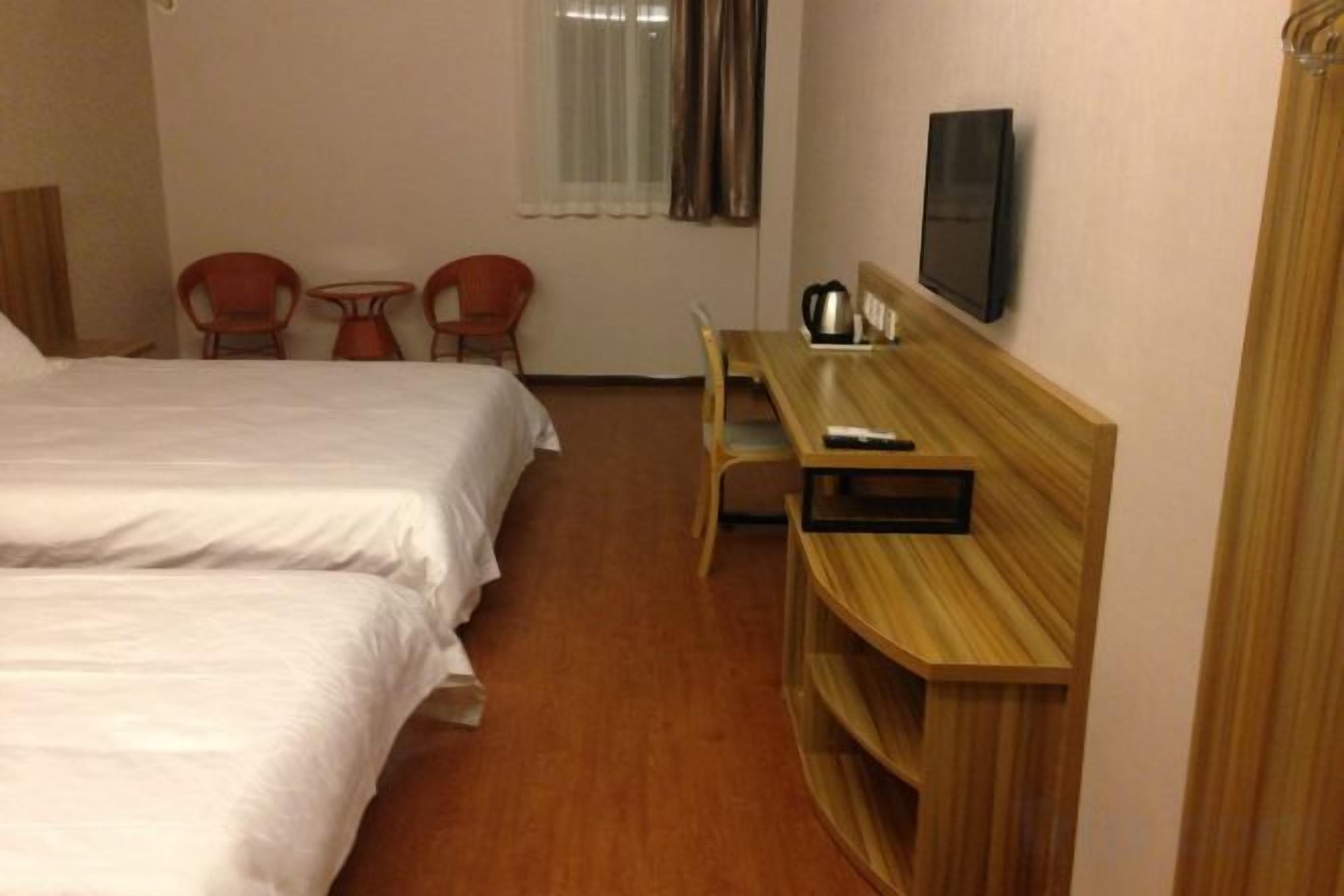 Une chambre d’hôtel avec deux lits, un bureau, une chaise et une petite table.