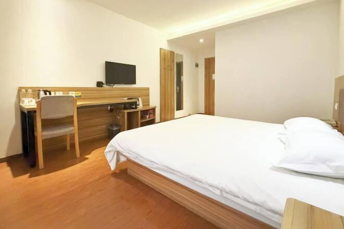 Ein Hotelzimmer mit Bett, Schreibtisch, Stuhl, Fernseher und Holzboden.