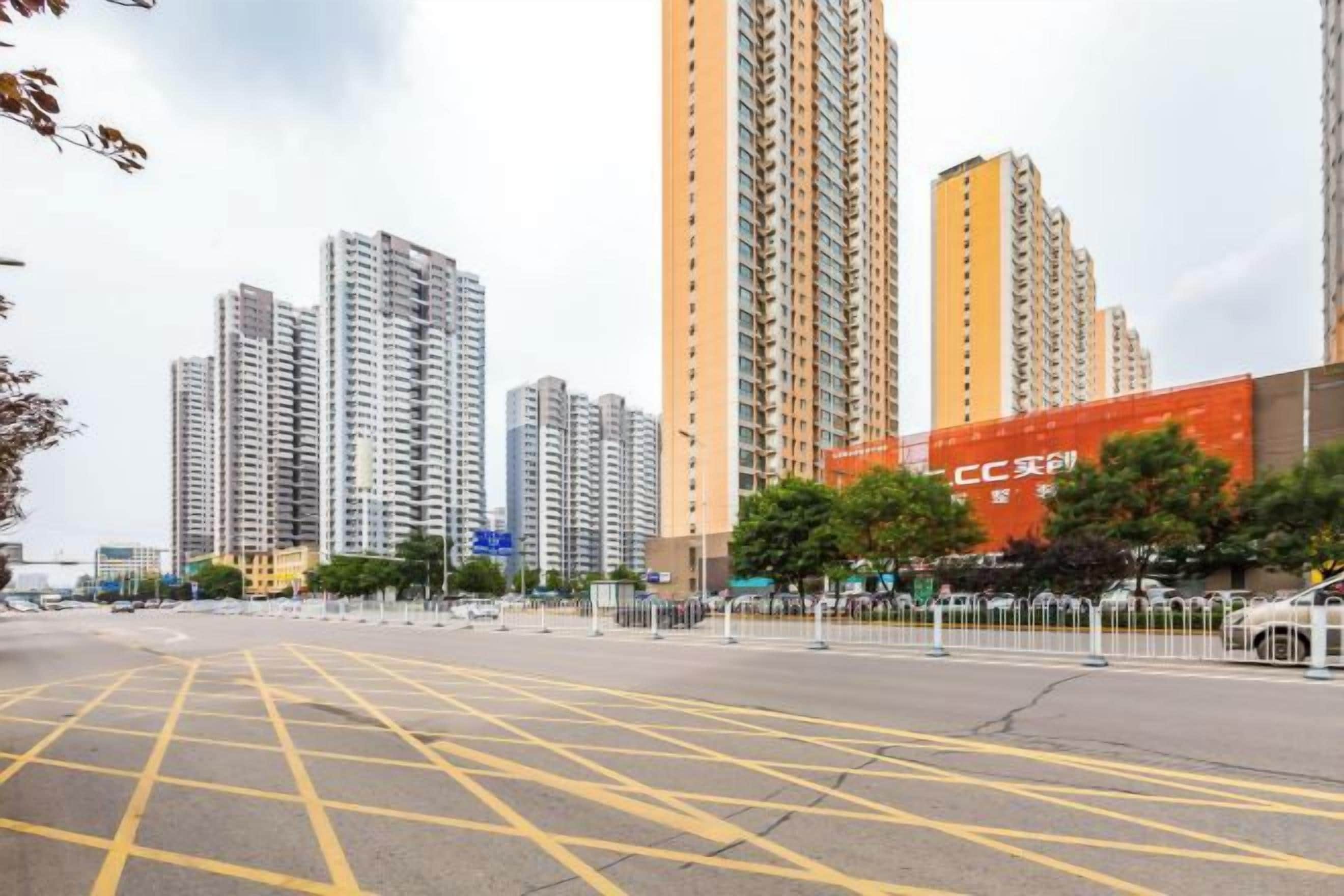 A cityscape with high-rise buildings, a clear sky, and a road with yellow lines.