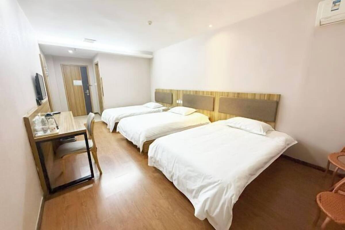 Ein Hotelzimmer mit zwei Betten, einem Schreibtisch mit Stuhl, einem Fernseher und einem kleinen Tisch mit Sitzgelegenheit.