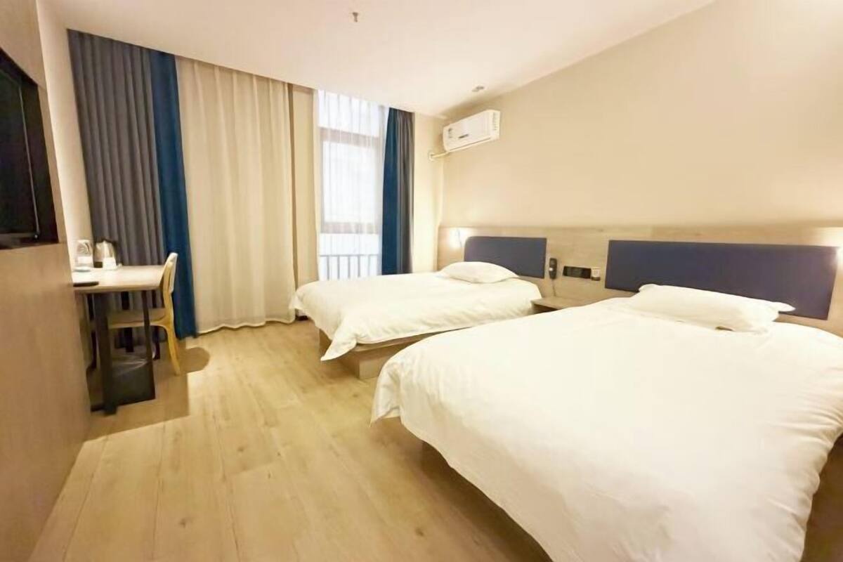 Ein Hotelzimmer mit zwei Betten, einem Schreibtisch und einem Stuhl.