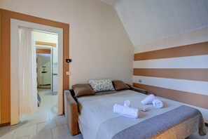 A hotel room with a bed, a bathroom visible through an open door, and a shower area.