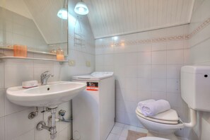 A bathroom with a white sink, a toilet, and a washing machine. - Apt. Gabriella: Studio in the Centre of Laveno (Laveno Mombello)