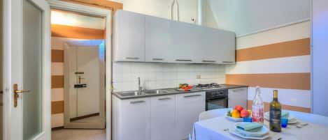 A modern kitchen with white cabinets, a gas stove, and a dining area with a table set for two.