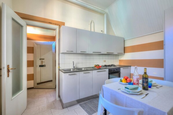 A modern kitchen with white cabinets, a gas stove, and a dining area with a table set for two.