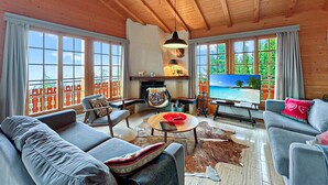 Ein geräumiges Wohnzimmer mit großem Fernseher, bequemen Sitzmöglichkeiten und Meerblick durch große Fenster.