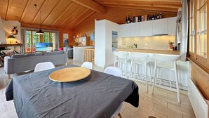 Eine moderne Küche mit weißen Schränken, einer Holzbalkendecke und einem Essbereich mit Tisch und Stühlen.