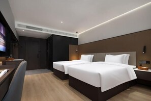 Une chambre d’hôtel moderne équipée de deux lits, d’un bureau et d’une télévision.