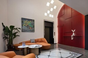 A modern lobby with a red accent wall, a seating area with orange sofas, a coffee table, and a large potted plant. - mutai Hotel Changsha (Changsha)