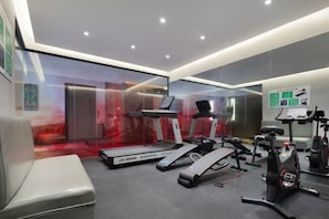 Ein modernes Fitnessstudio mit Laufbändern, einem Ergometer und einer Trainingsbank.