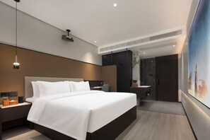 Une chambre d’hôtel moderne dotée d’un grand lit, d’une table de chevet, d’un bureau, d’une chaise, d’une salle de bain avec un comptoir en marbre et d’une grande œuvre d’art accrochée au mur.