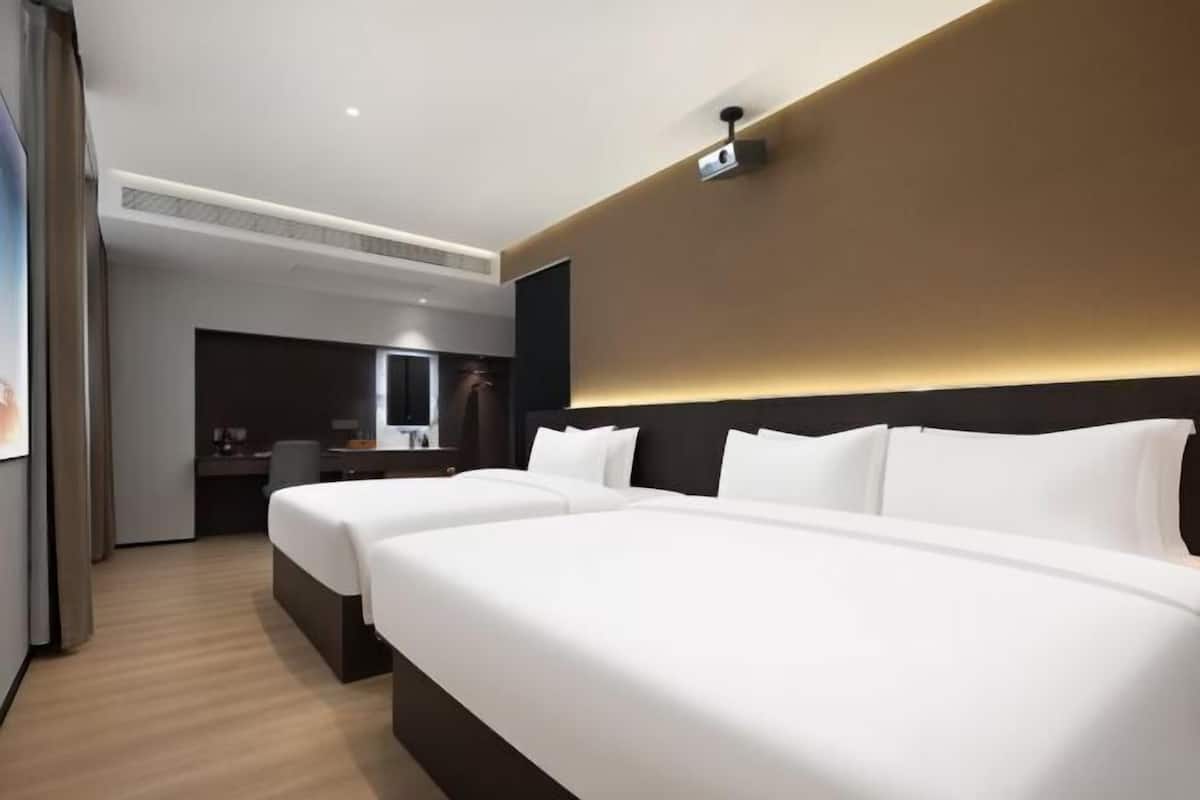 Quarto de hotel com duas camas, uma mesa e um espelho.