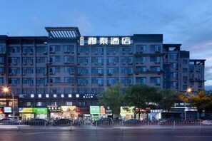 A multi-story hotel with a prominent sign, multiple balconies, and a parking area in front. - mutai Hotel Changsha (Changsha)