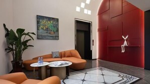 A modern lobby with a red accent wall, a painting, a sofa, a coffee table, and a potted plant. - mutai Hotel Changsha (Changsha)