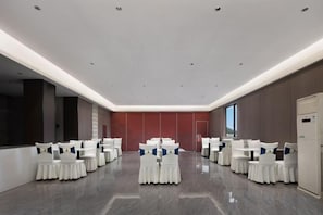 A conference room with rows of white tables and chairs, a red accent wall, and a modern ceiling design. - mutai Hotel Changsha (Changsha)
