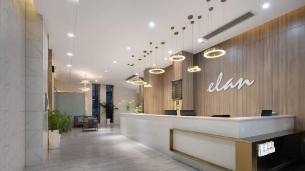 A modern reception area with a wooden reception desk, multiple pendant lights, and a visible sign that reads "elan". - mutai Hotel Changsha (Changsha)