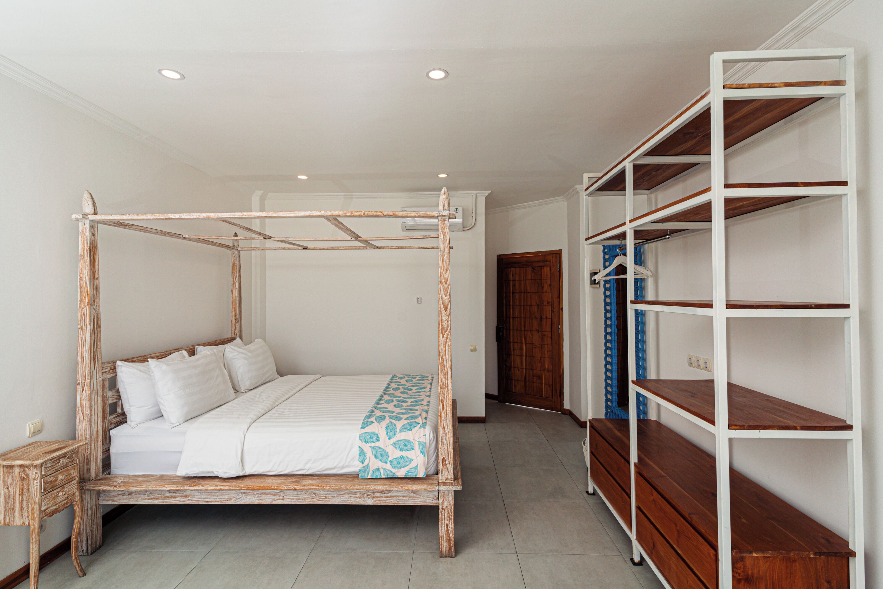 A bedroom with a wooden four-poster bed, a wooden wardrobe, and a white wall.