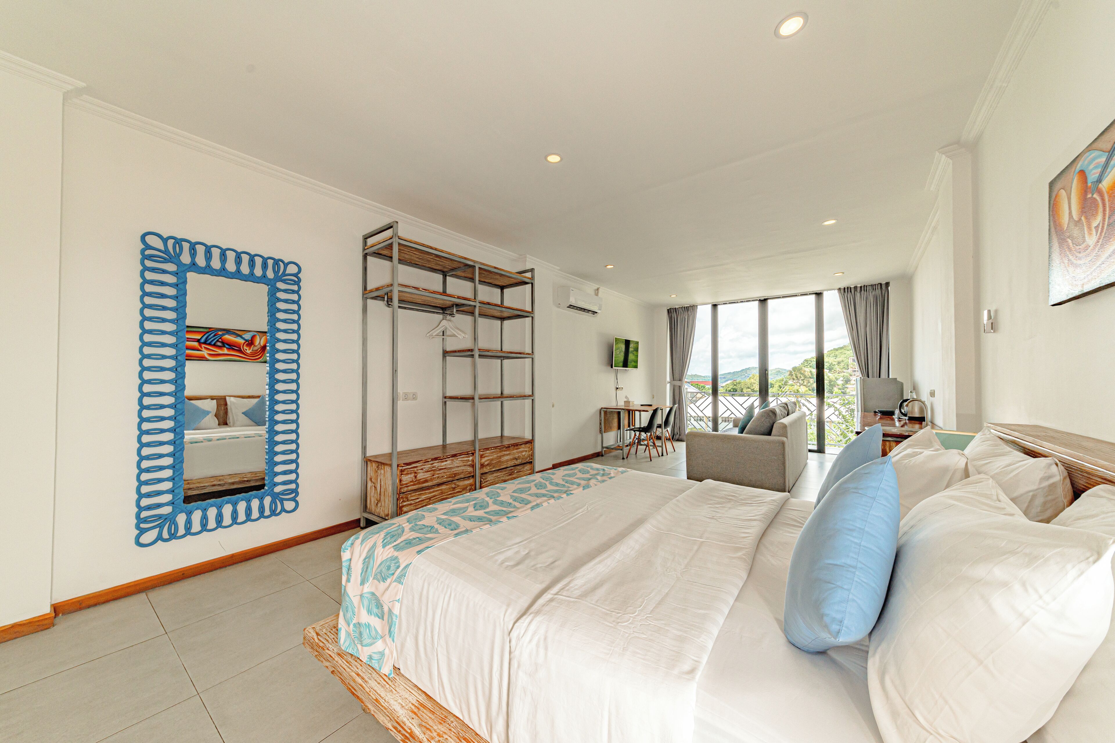 A spacious bedroom with a large bed, a wardrobe, a desk with a chair, and a view of the outdoors.