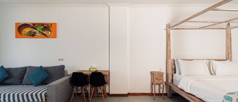 Una habitación con cama, sofá, una mesita con sillas y un cuadro en la pared.