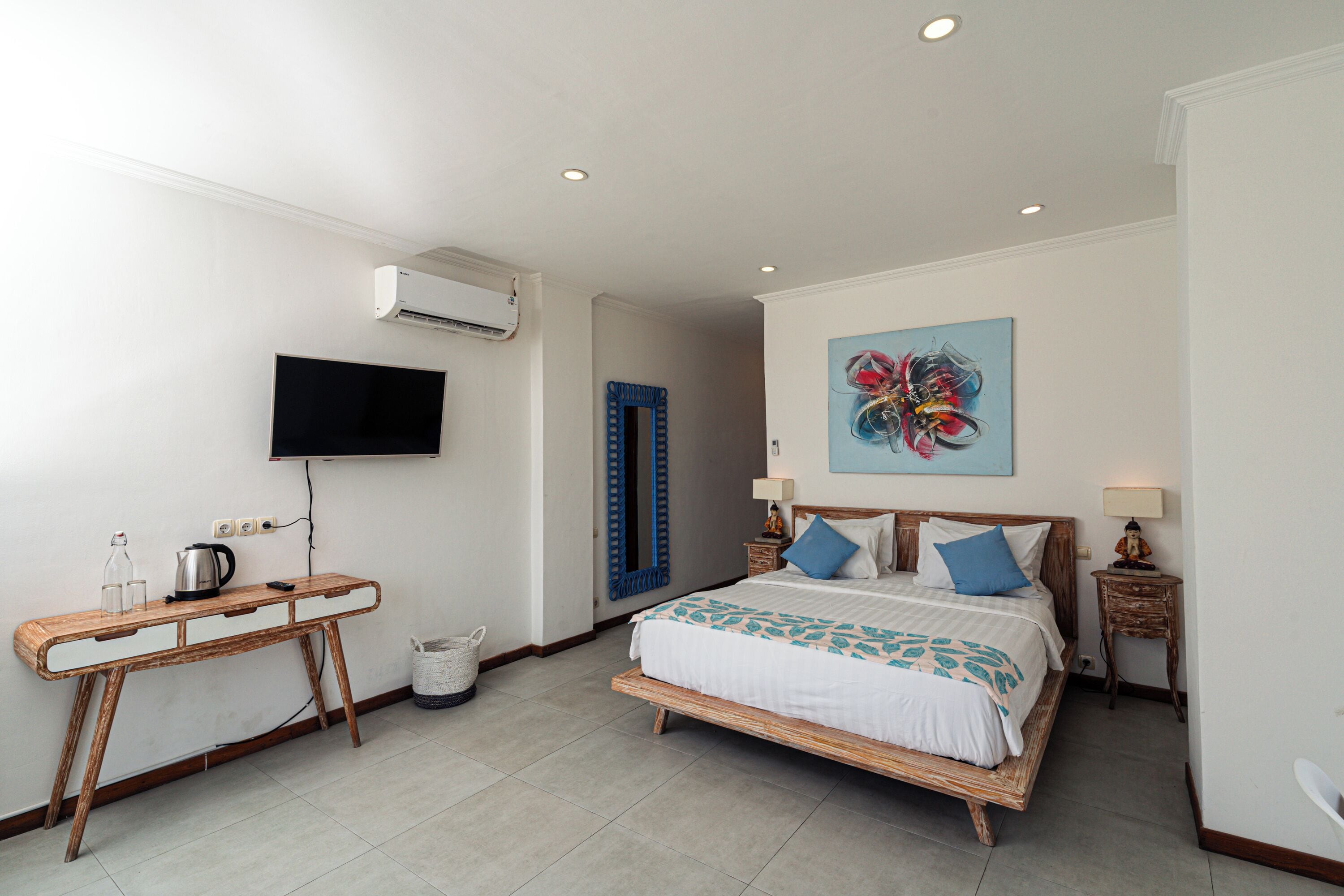 Un dormitorio con cama, mesitas de noche, escritorio, televisor y aire acondicionado instalado en la pared.