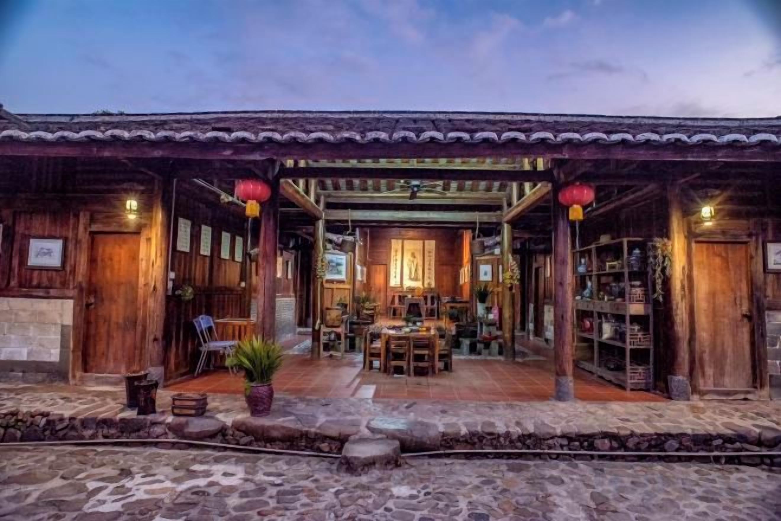 A traditional wooden building with a covered patio, a dining area, and a display of items.