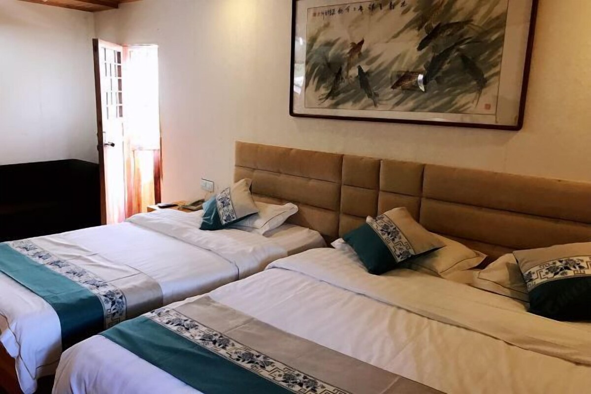 A hotel room with two beds, a headboard, a framed artwork, and a door.
