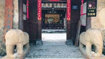 Una puerta tradicional china con elefantes de piedra, un tejado de tejas y un cartel.
