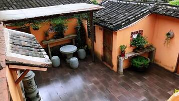A traditional courtyard with a tiled roof, a small table, and potted plants.