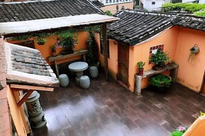 A traditional courtyard with a tiled roof, a small table, and potted plants. - Painting Base in Yun Shui Trackway (Nanjing County)