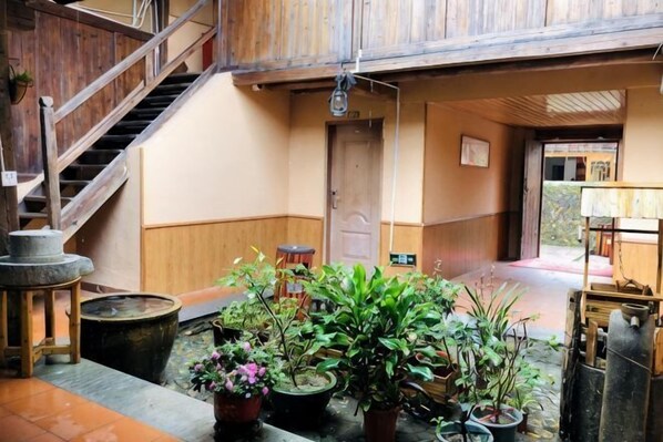 A traditional Japanese interior with a wooden staircase, potted plants, and a wooden door.