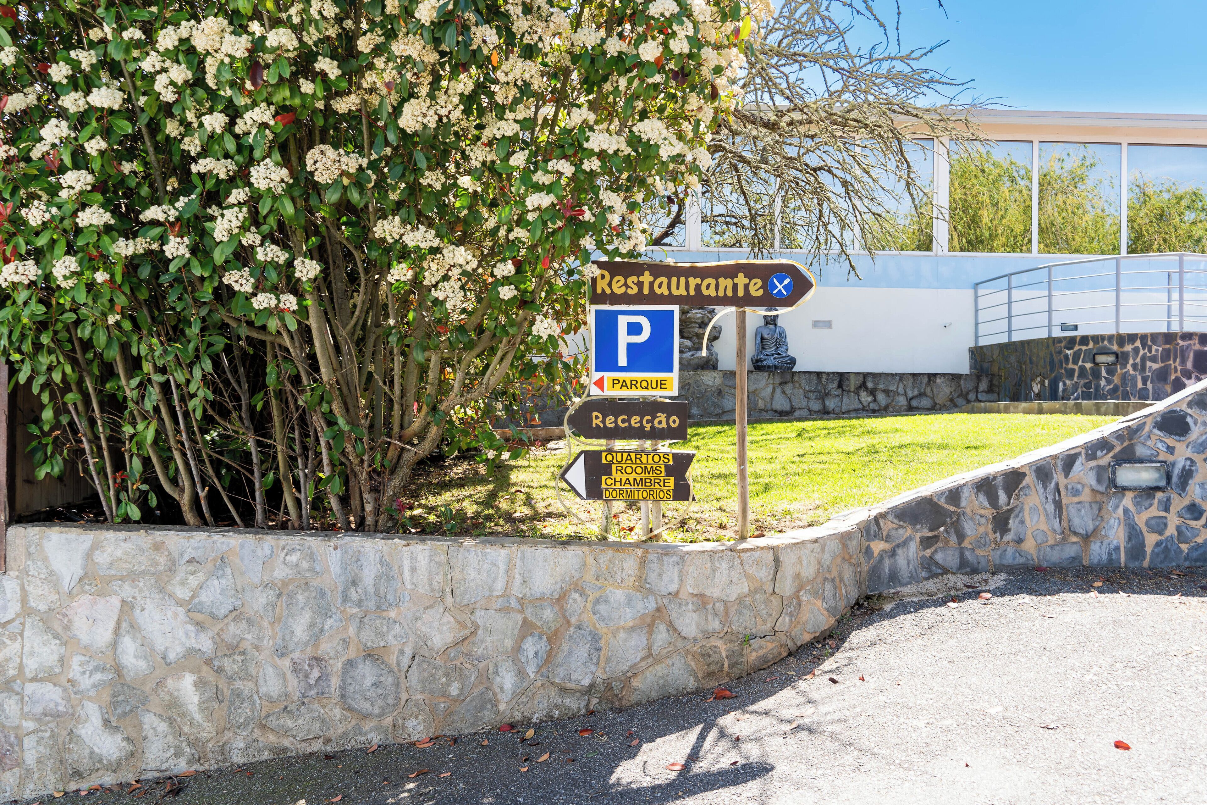 A stone wall with a sign indicating a restaurant, parking, and a reception area.