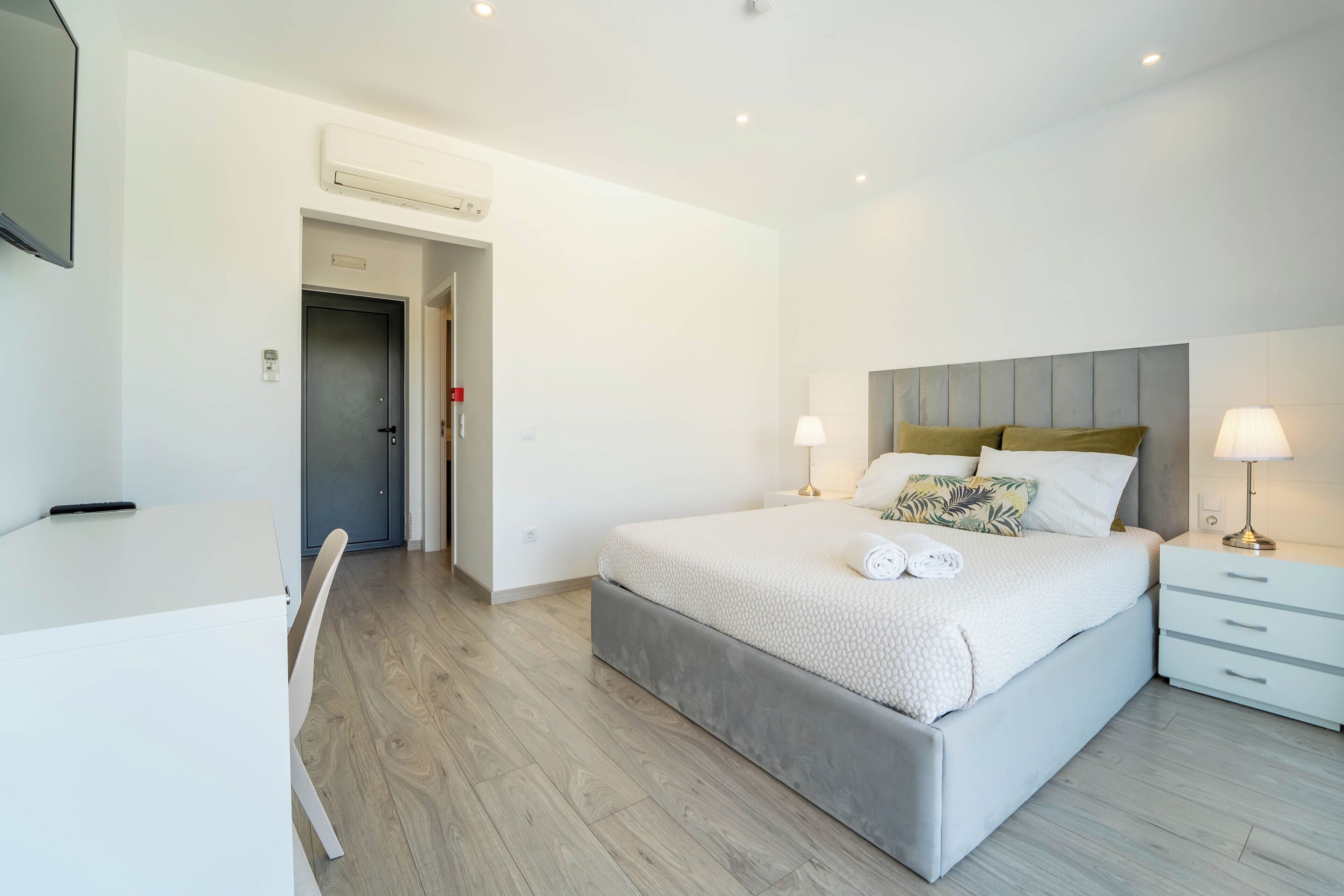 Un dormitorio moderno con cama, mesitas de noche, un escritorio y una silla.