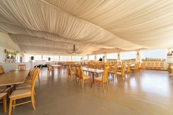 A large indoor dining area with high ceilings and a chandelier. Tables and chairs are arranged in rows. - Quinta Solar da Portela (Almodôvar)