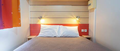 Un dormitorio con una cama, dos lámparas de noche, una mesita de noche y un cabecero rojo y beige.