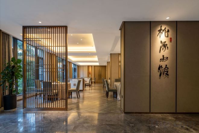 Vestíbulo de hotel con recepción, zona de estar y pared decorativa con caligrafía.