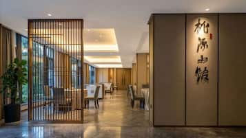 Vestíbulo de hotel con recepción, zona de estar y pared decorativa con caligrafía.