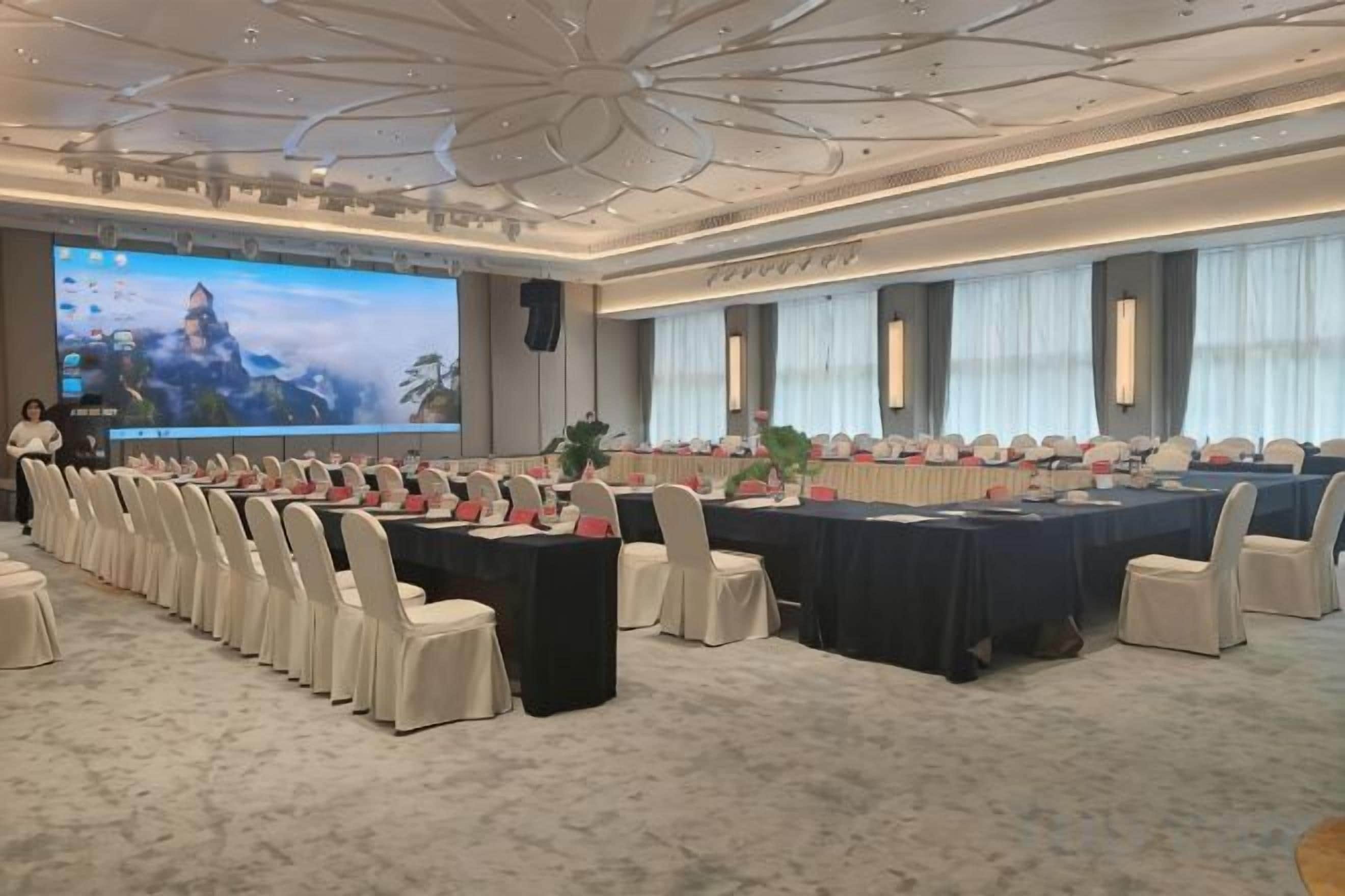 A conference room with a long table, chairs, and a large screen.