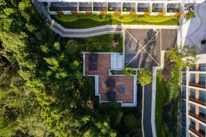 An aerial view of a building with a rooftop terrace, surrounded by greenery and adjacent to a road. - Shenxianju Narada Resort & Spa (Xianju)