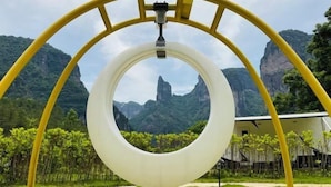 Un parque infantil con una estructura de tobogán circular, con montañas y vegetación de fondo.