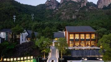 A hotel with a modern design, situated in a mountainous area with a view of rocky hills.