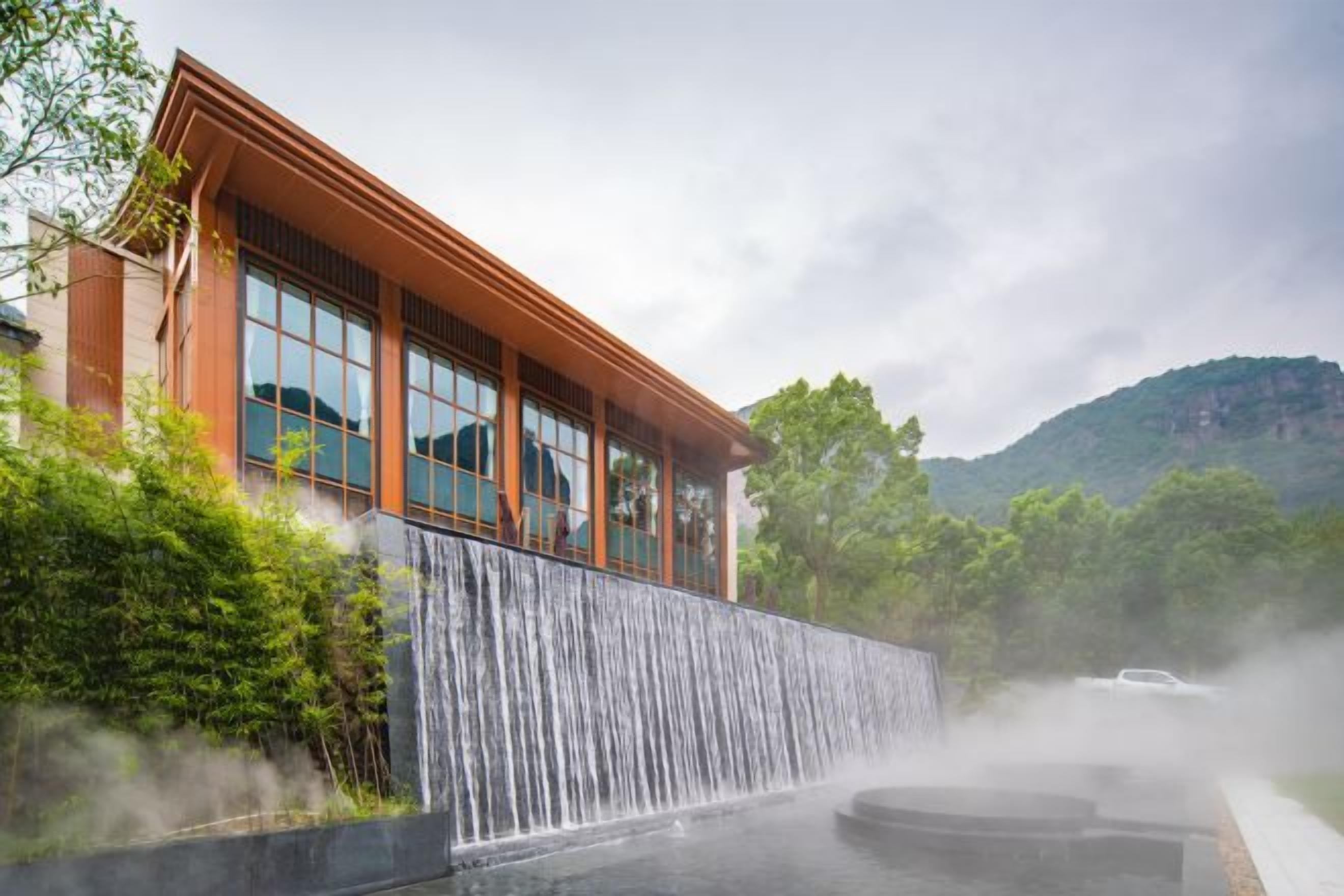 A modern building with large windows and a waterfall feature in front.